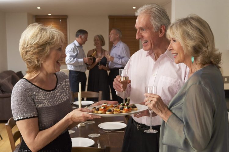 Woman Serving Hors D'oeuvres To Her Guests and Friends At A Dinner Party